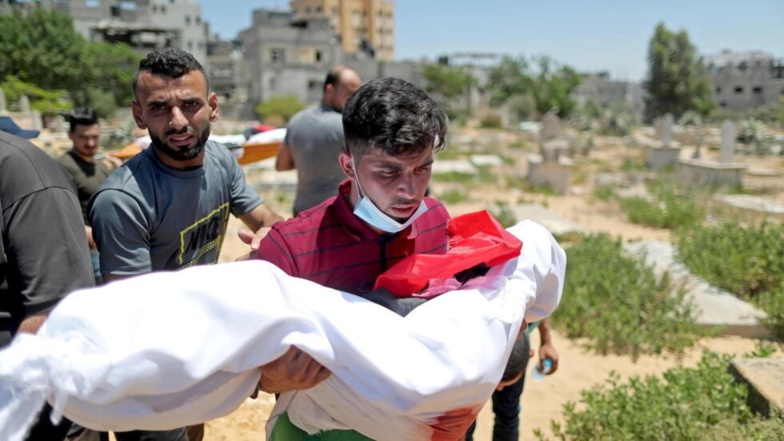 Un homme porte le corps d'un enfant palestinien tué lors d'une flambée de violence, lors de ses funérailles dans un cimetière du nord de la bande de Gaza le 15 mai 2021. REUTERS - SUHAIB SALEM